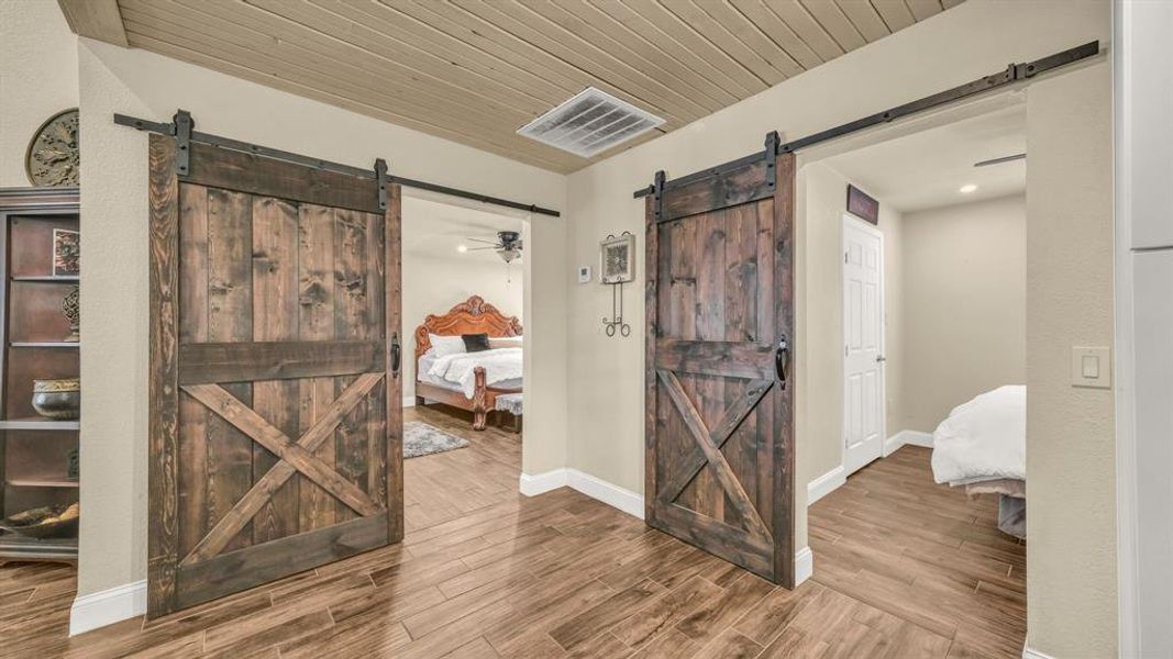 Corridor with wood ceiling, a barn door, and hardwood / wood-style floors