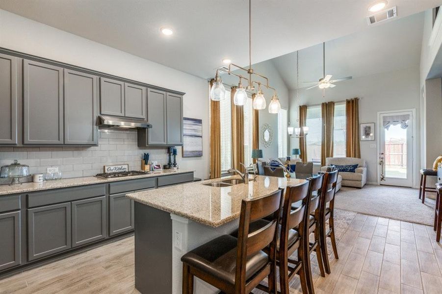 Kitchen featuring light hardwood / wood-style floors, a kitchen island with sink, gray cabinetry, stainless steel gas stovetop, and sink