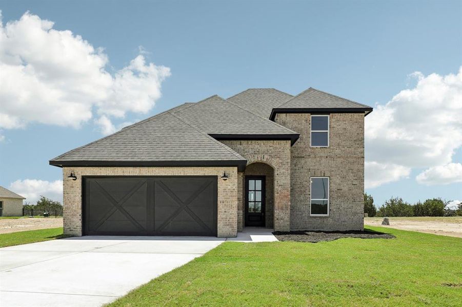 View of front of home with a garage and a front lawn