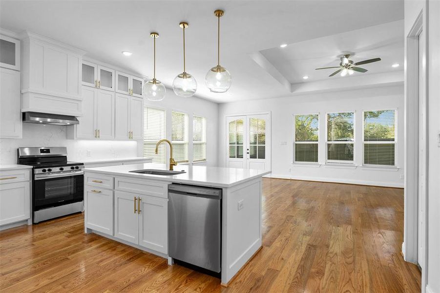 Kitchen with appliances with stainless steel finishes, sink, light hardwood / wood-style floors, and white cabinets