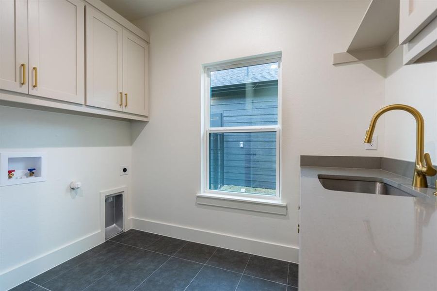 Laundry area featuring hookup for an electric dryer, dark tile patterned floors, hookup for a washing machine, cabinets, and sink