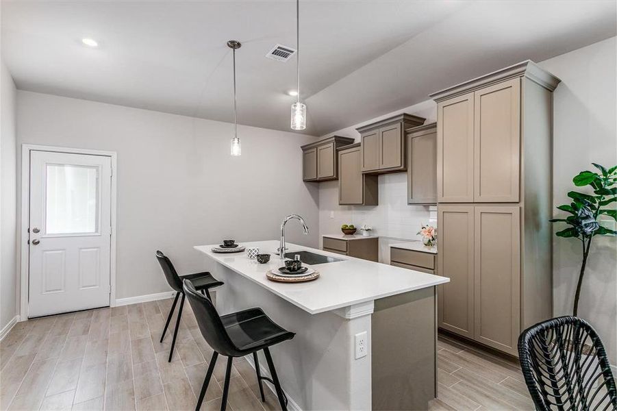 Enjoy casual dining or morning coffee at the kitchen island's convenient bar seating. This beautifully designed space features modern pendant lighting, a deep stainless-steel sink, and ample counter space, making it perfect for meal prep, dining, or hosting guests. **This image is from another Saratoga Home - Mockingbird floorplan.**