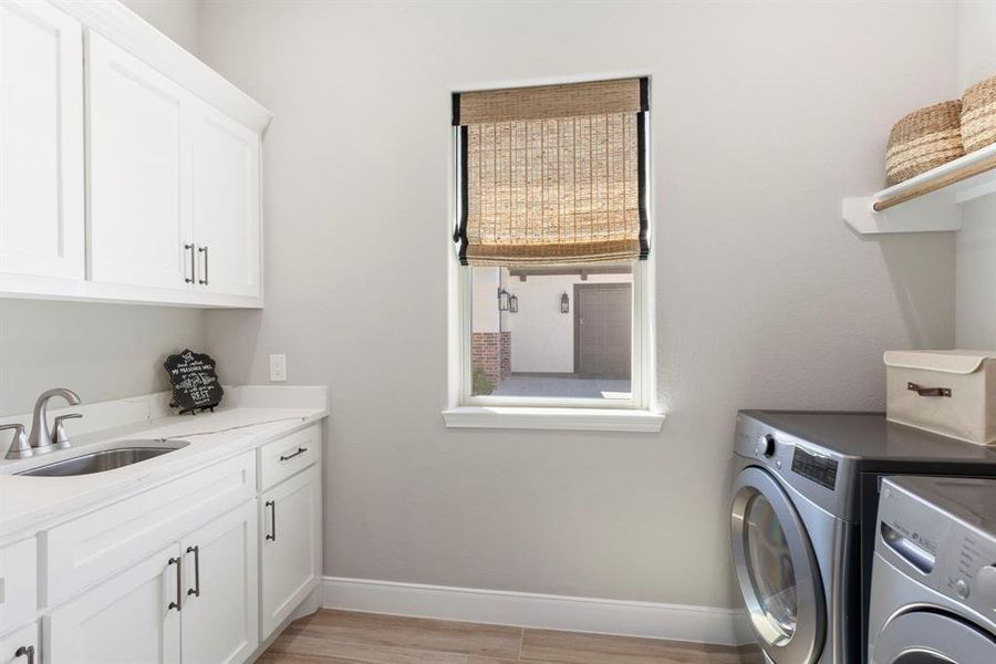 This laundry room is fantastic! With a sink, countertop space, storage, and hanging space, it is perfect for all your daily home needs.