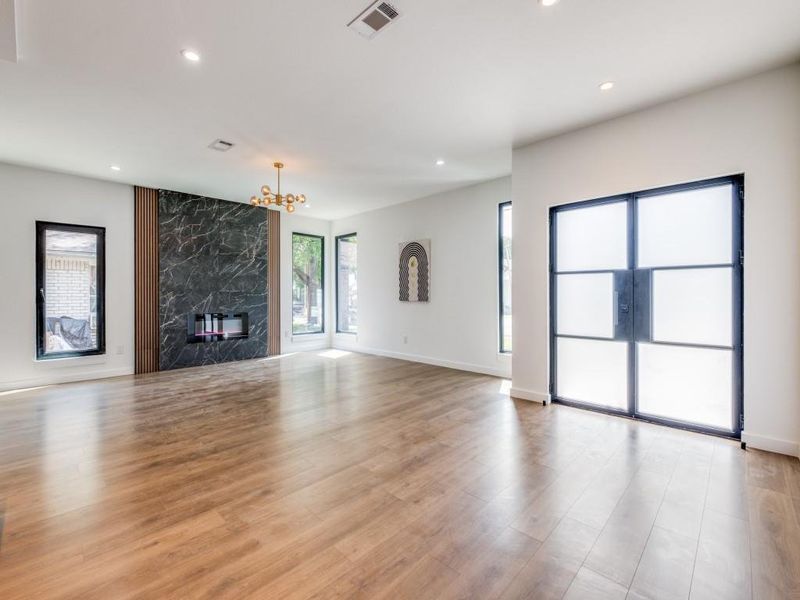 Unfurnished living room featuring an inviting chandelier, a high end fireplace, and light hardwood / wood-style floors