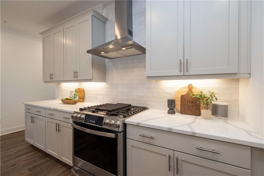 Kitchen featuring gas range, decorative backsplash, light stone countertops, dark hardwood / wood-style flooring, and wall chimney exhaust hood not the actual unit