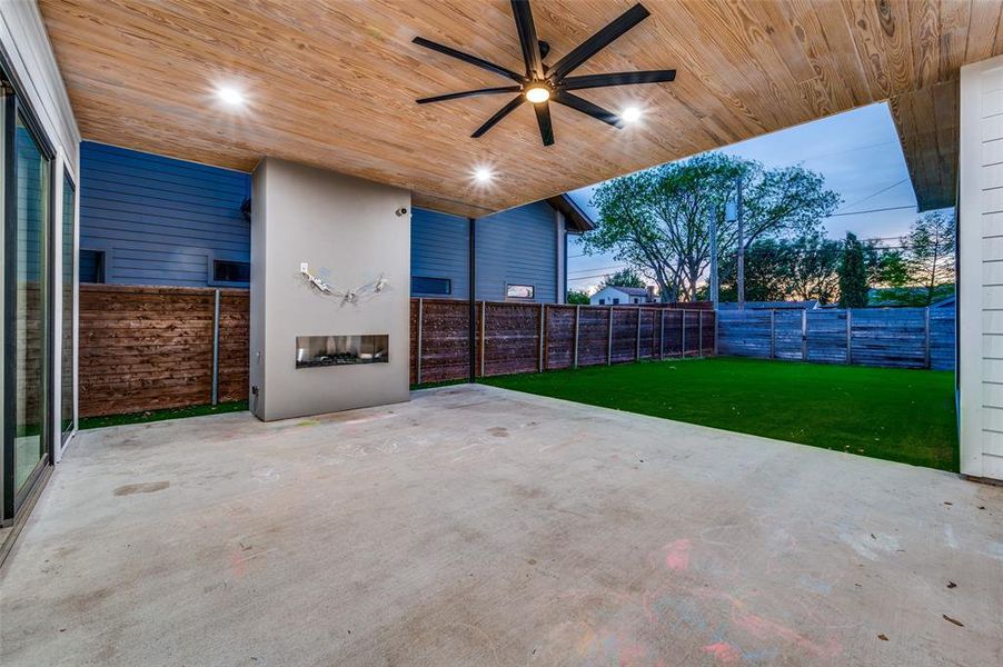 Patio terrace at dusk featuring a yard and ceiling fan