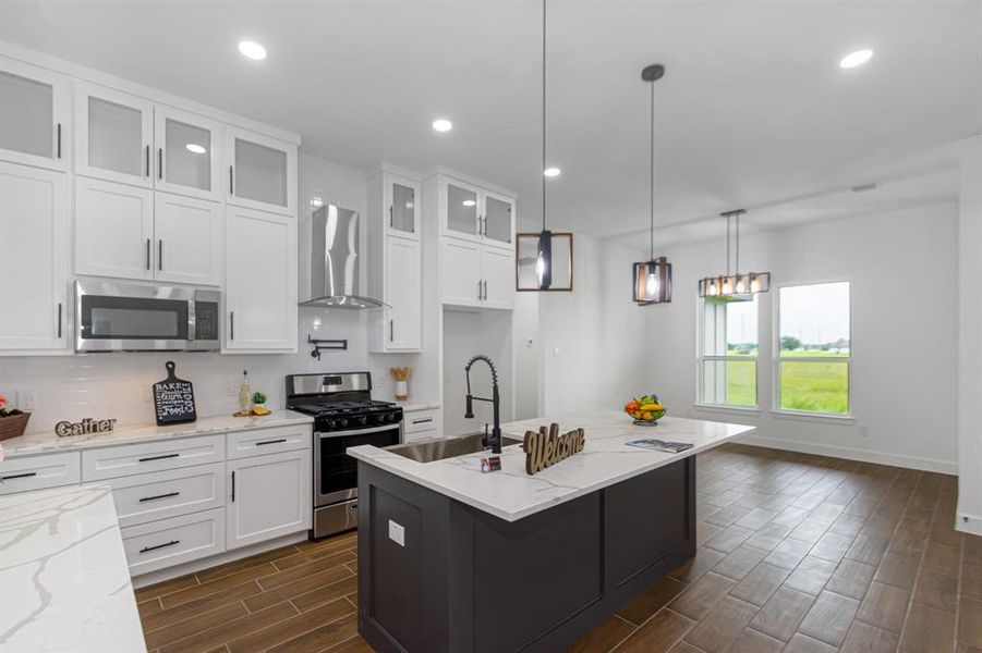 Kitchen open to dining area.  Stainless steel appliances, modern plumbing fixtures including a pot filler above the stove.