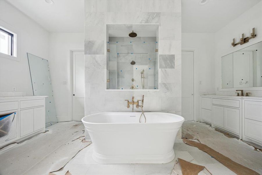 It is perfection!  This primary bath will be treasured.  The large shower with rainfall shower head, hand-held and a fixed wall mounted headed has entry access from both sides.  The gorgeous soaking tub is a true beauty.  The doors on either side of the shower are primary closet access.  Photo as of 9/3/2024