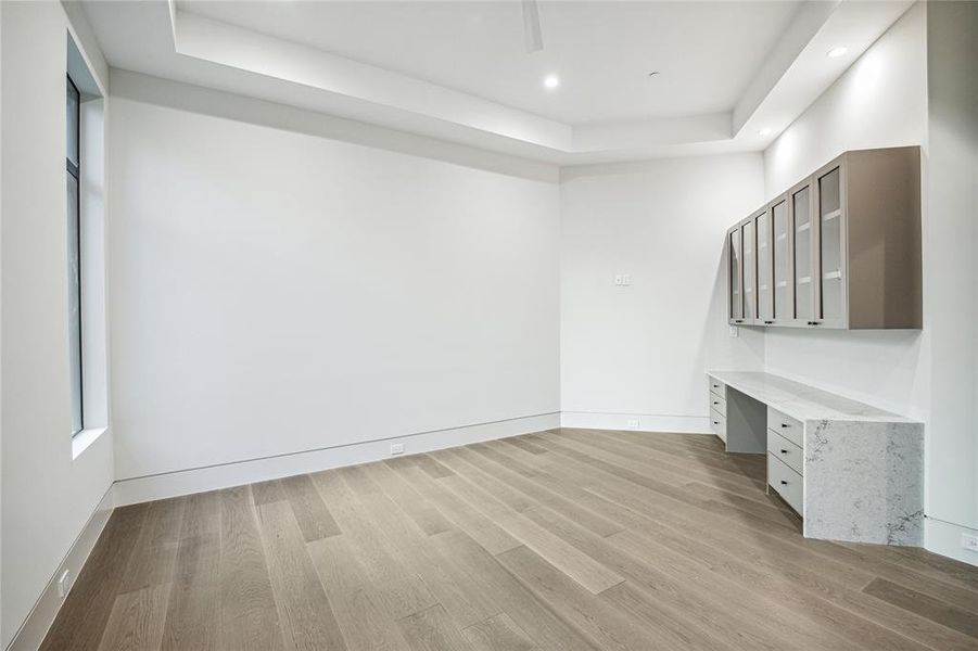 Step into the welcoming embrace of the first floor  guest bedroom, where stained White Oak Engineered Hardwood Flooring exudes warmth and charm. A Minka-Aire White Ceiling Fan with Remote in Matte White ensures optimal comfort, while the walk-in closet, complete with dual levels for hanging and storage shelving, offers convenience and organization. Sunlight pours in through windows offering southwestern exposures, bathing the space in natural light and creating a serene ambiance perfect for restful nights