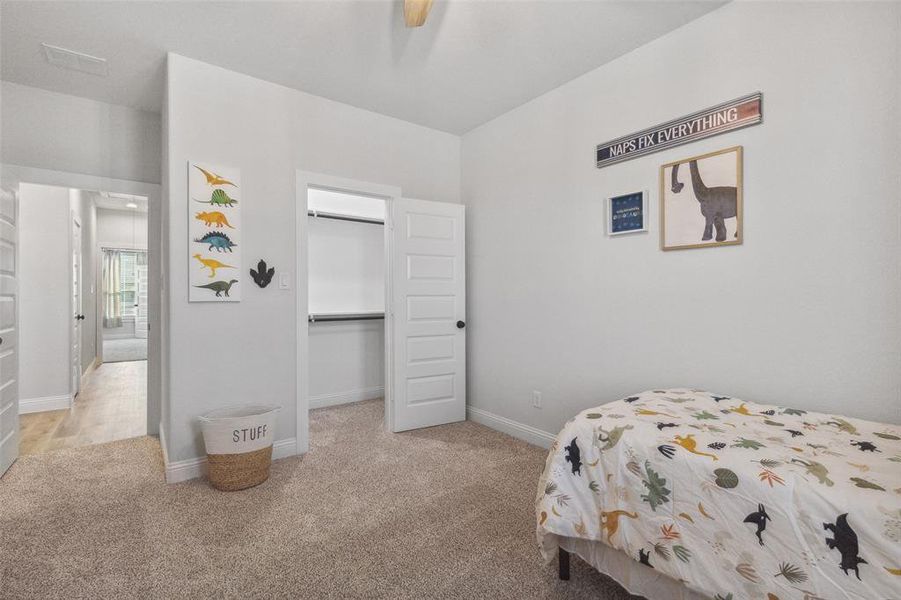 Bedroom with a walk in closet, light colored carpet, a closet, and ceiling fan