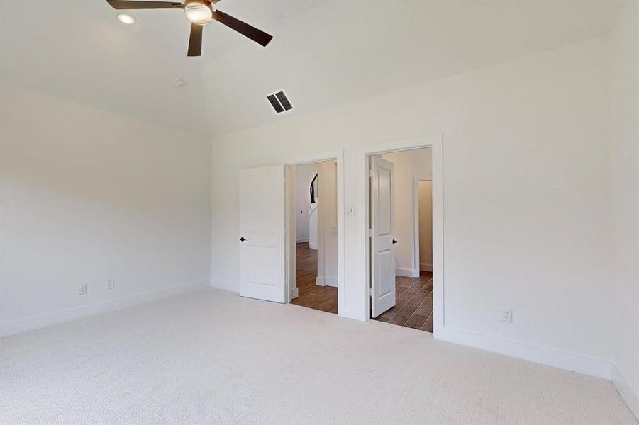 Unfurnished bedroom with dark carpet, high vaulted ceiling, and ceiling fan