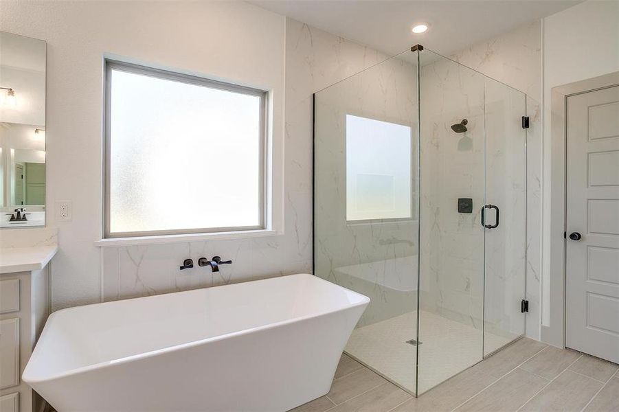 Bathroom featuring vanity and separate shower and tub