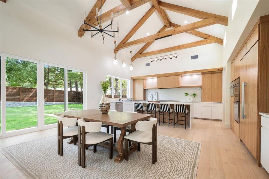 Dining area with light hardwood / wood-style floors, sink, and high vaulted ceiling