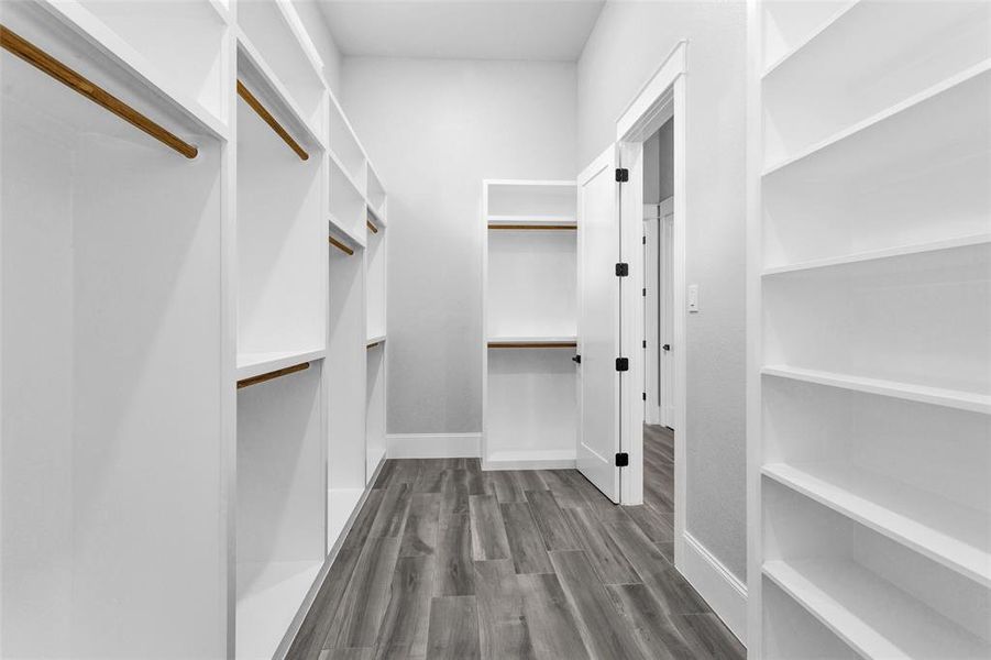 Primary Walk-In Closet #1. Both closets are finished with custom built-ins offering an amazing amount of hang space and shelf space, beautiful moldings and finishings.