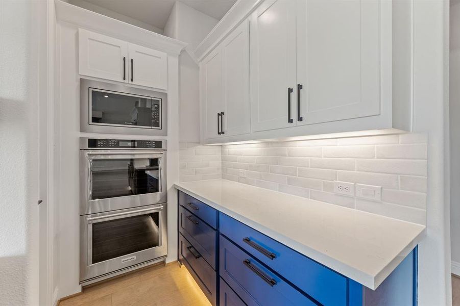 Kitchen featuring white cabinetry, light hardwood / wood-style flooring, backsplash, appliances with stainless steel finishes, and blue cabinetry