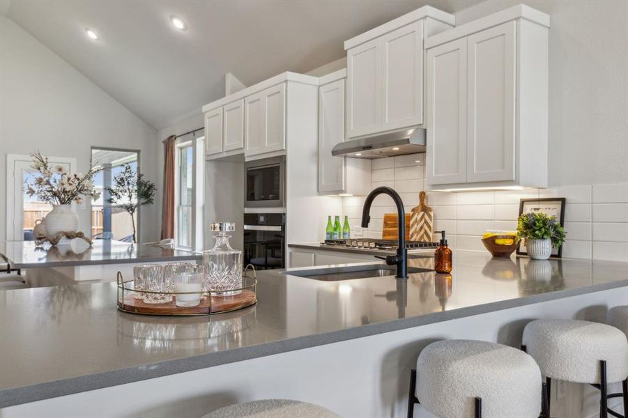 Kitchen featuring white cabinets, kitchen peninsula, a breakfast bar area, and oven