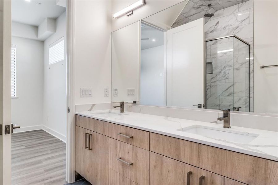 Bathroom featuring double sink vanity, hardwood / wood-style flooring, and a shower with door