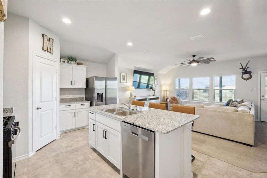 Kitchen with an island with sink, sink, stainless steel appliances, and white cabinets