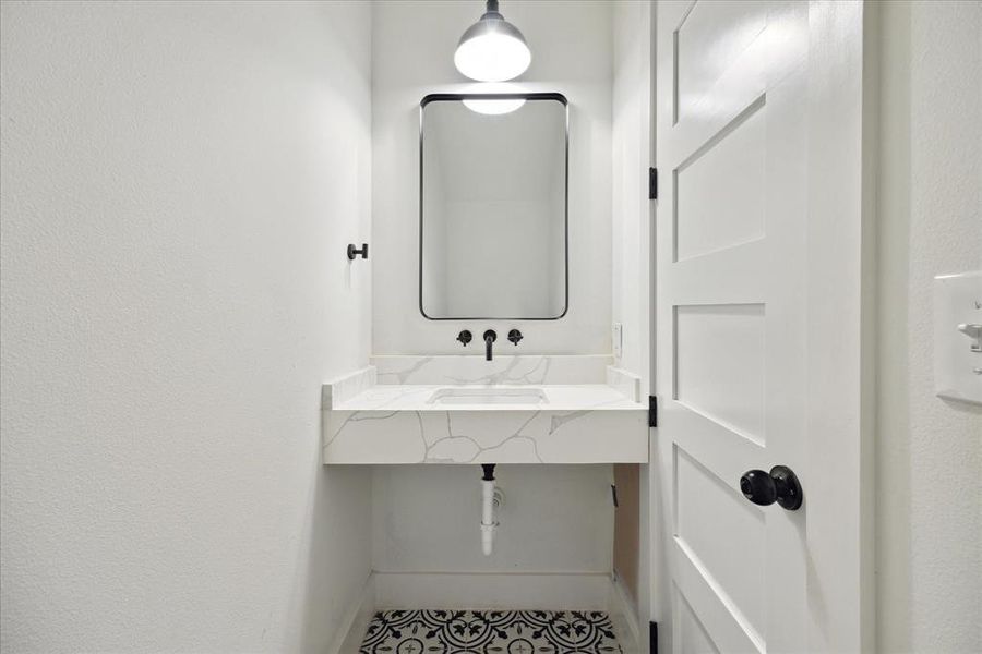 The half bathroom features a spacious countertop and tile floors.