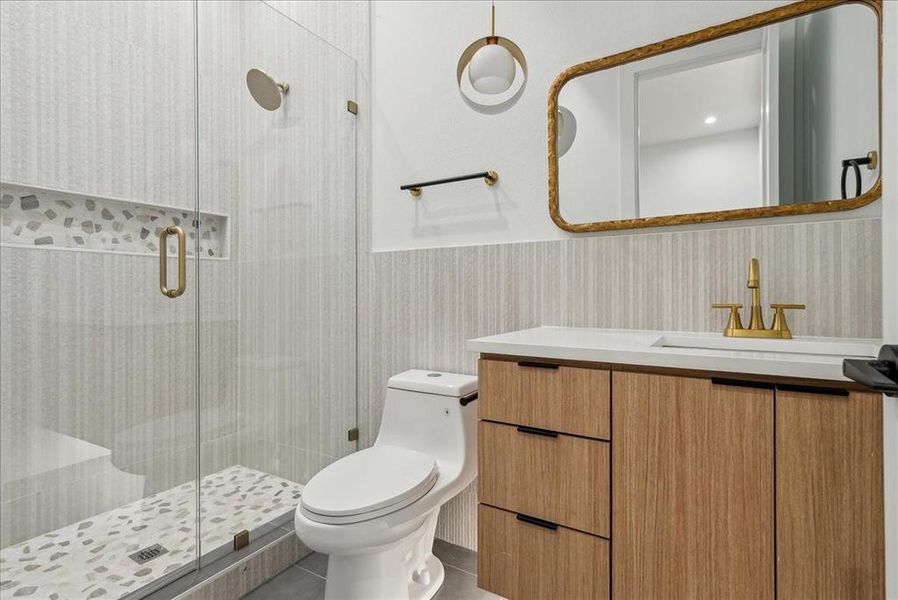 Bathroom featuring tile patterned flooring, a shower with shower door, vanity, and toilet