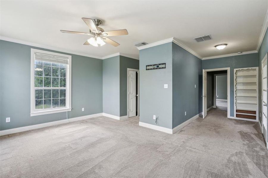 Carpeted room with ceiling fan and ornamental molding
