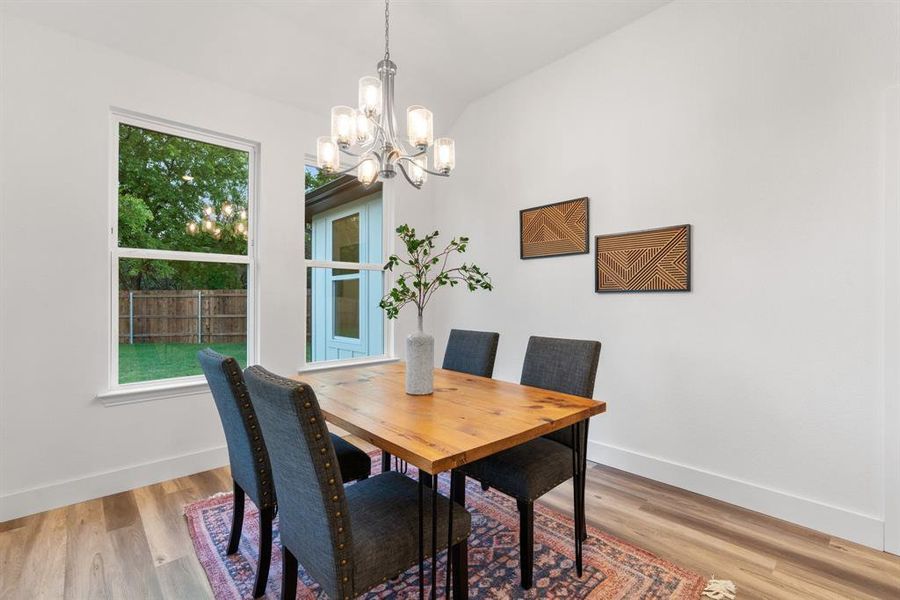 Dining area with a notable chandelier, light hardwood / wood-style flooring, and lofted ceiling