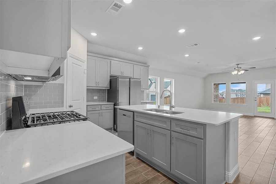Kitchen featuring gray cabinets, ceiling fan, tasteful backsplash, stainless steel appliances, and sink