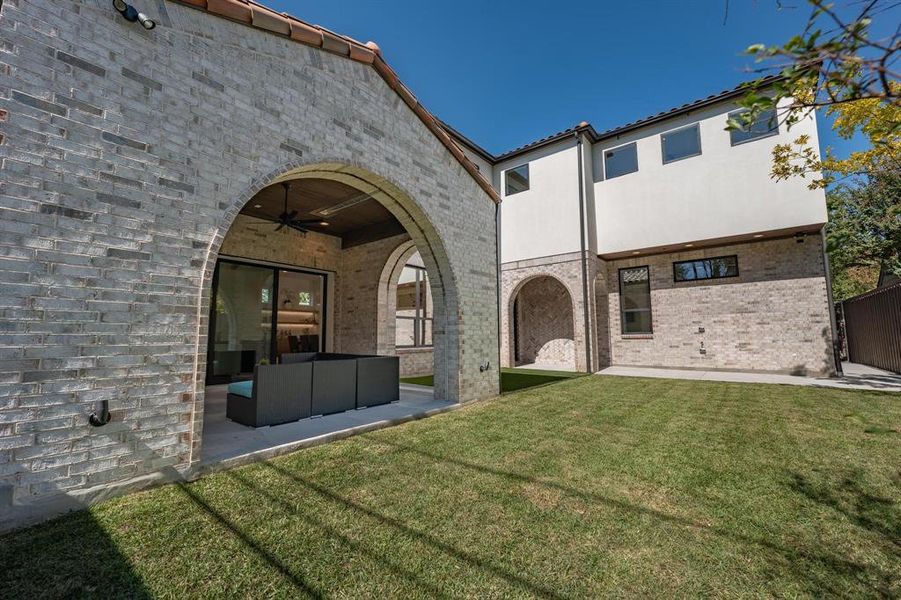 Back of house featuring an outdoor living space, a yard, a patio area, and ceiling fan