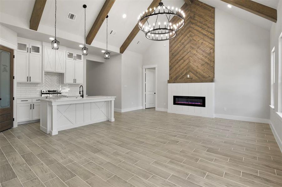 Kitchen with white cabinetry, light hardwood / wood-style floors, beamed ceiling, and decorative light fixtures