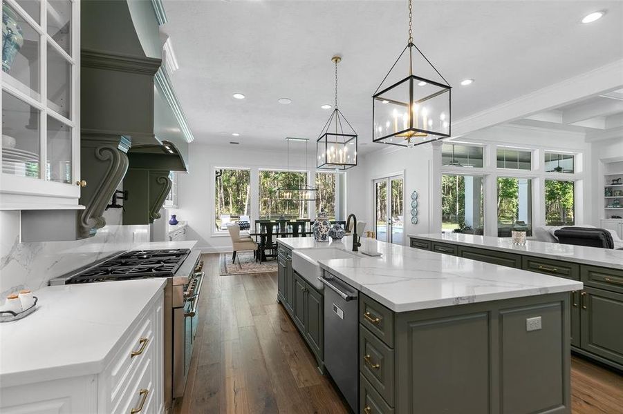 This functional layout of this kitchen is quite extraordinary! Large farmhouse sink, custom built vent hood, and convenient pot filler are featured! The pendant lighting illuminates the island and adds a modern feel!