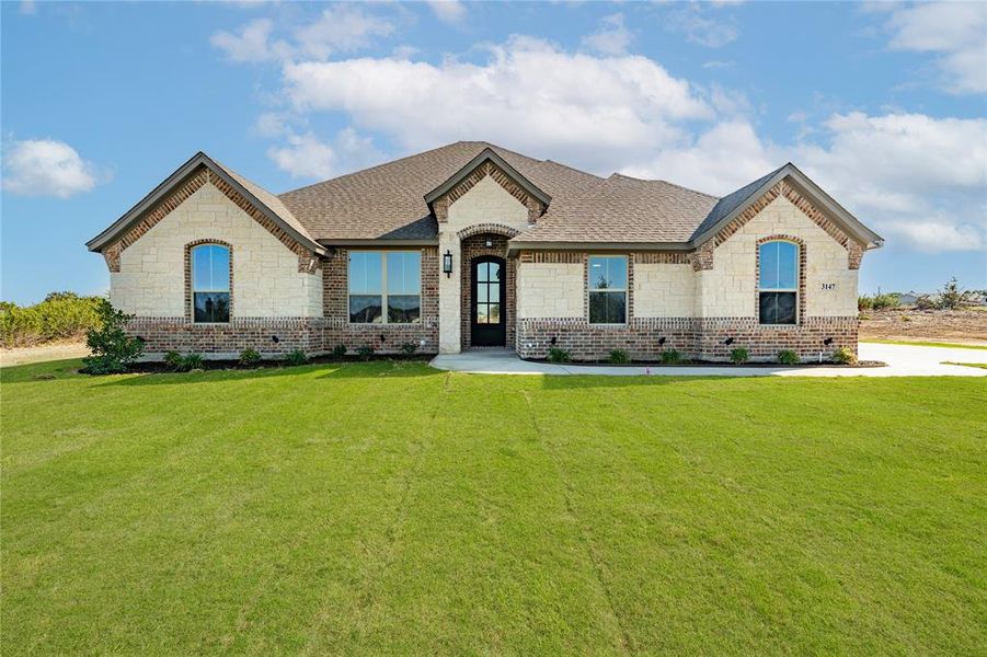 French country inspired facade with a front yard