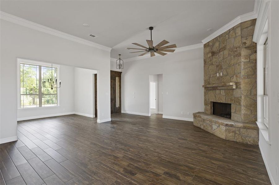 Unfurnished living room with ornamental molding, a fireplace, ceiling fan, and dark wood-type flooring