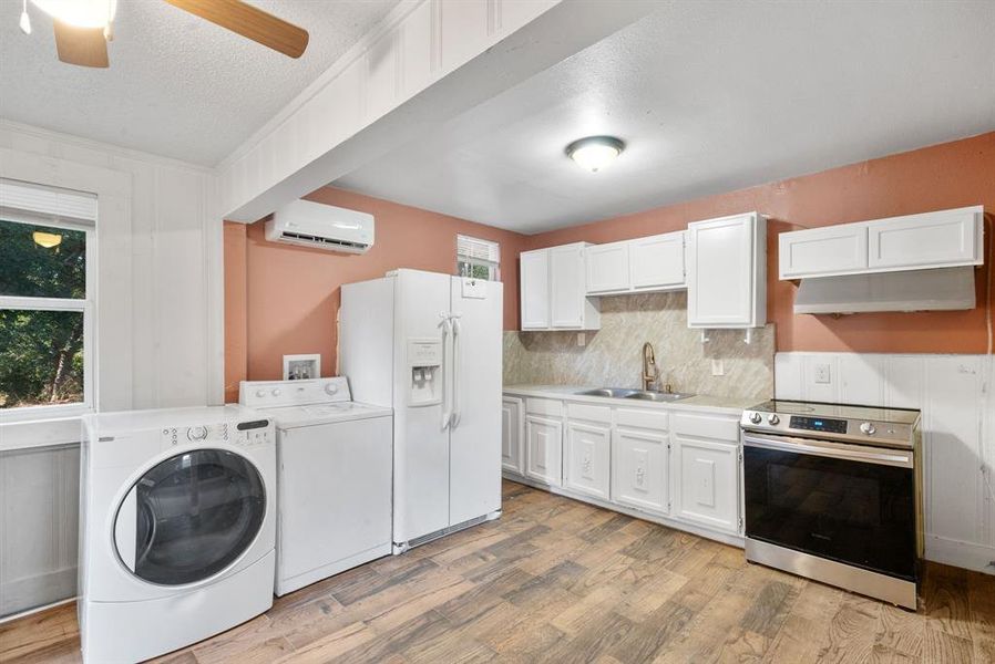 Kitchen with ceiling fan, sink, independent washer and dryer, stainless steel range oven, and white fridge with ice dispenser