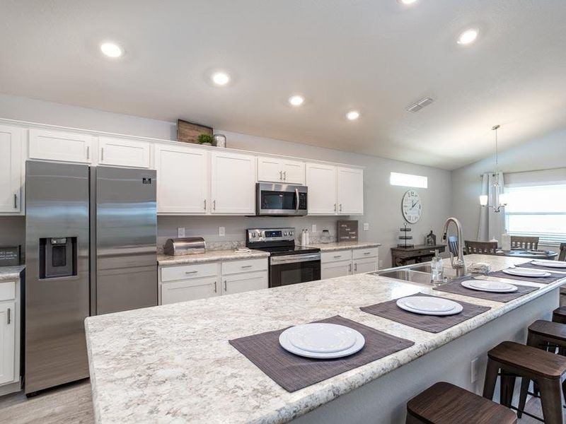 Open kitchen with counter-height island and walk-in pantry - Serendipity home plan by Highland Homes