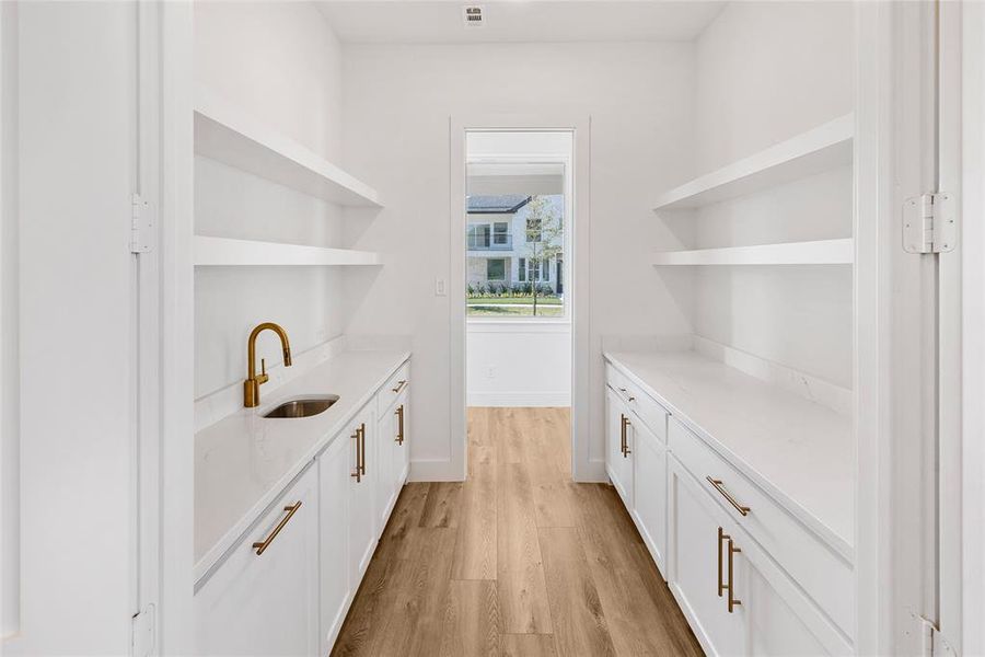 Bar featuring light hardwood / wood-style floors, white cabinets, and sink