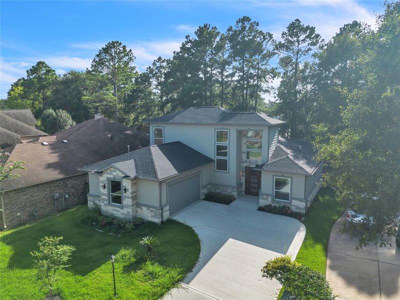 Modern two-story house with stone accents, large windows, surrounded by beautiful trees locate in a cul-de-sac.