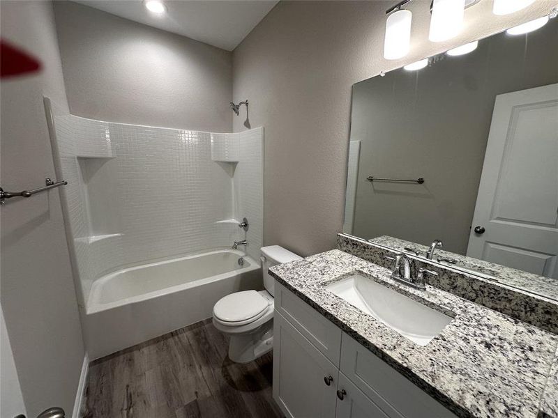 Full bathroom with vanity, toilet, hardwood / wood-style floors, and shower / washtub combination