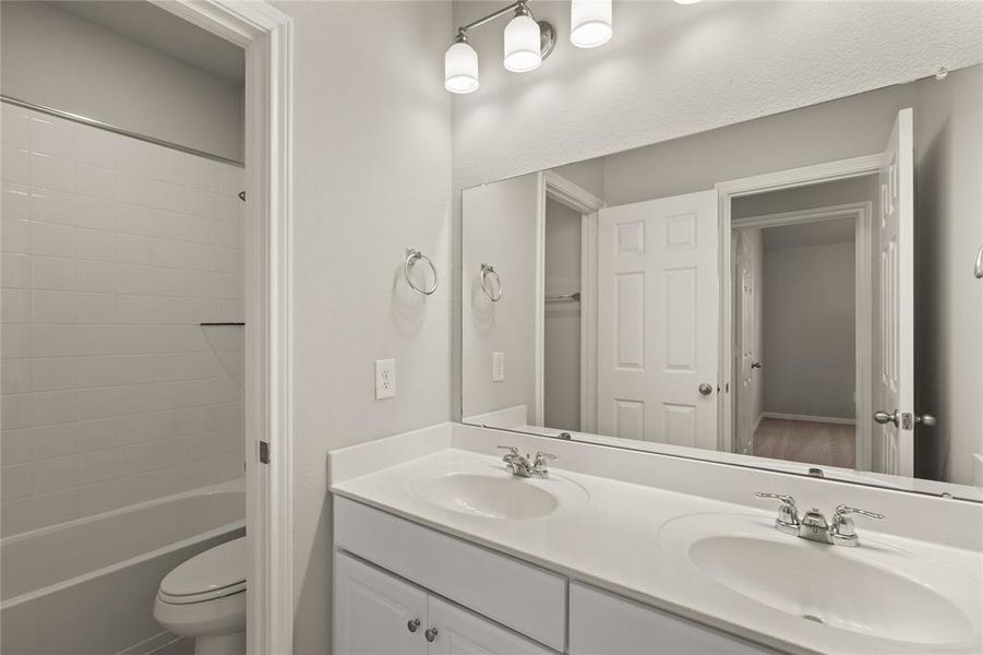 The secondary bath features tile flooring, white cabinetry and light countertops and a shower/tub combo. Perfect for accommodating any visiting family and friends.