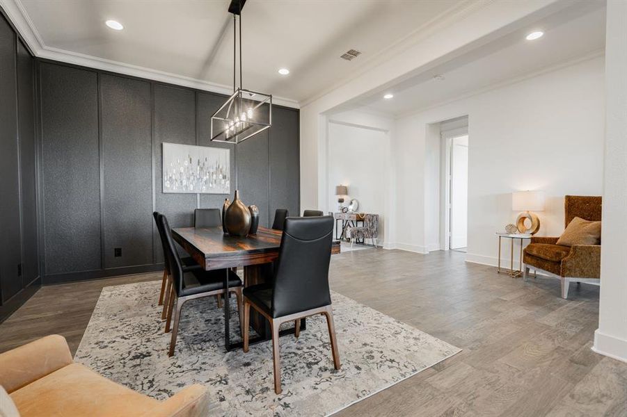 Dining area with ornamental molding, hardwood / wood-style floors, and a notable chandelier