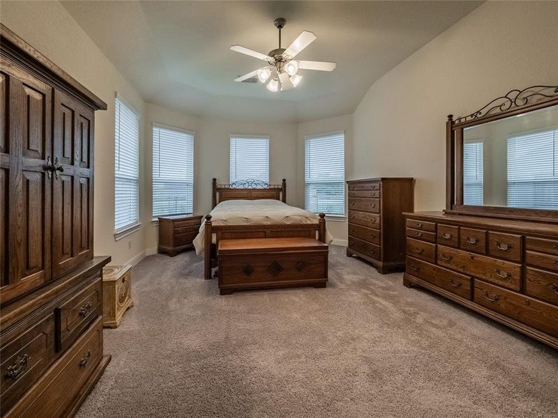 the primary bedroom is off the family room, very spacious with bay windows, ceiling fan, this is a queen size bed so you can see there is plenty of room