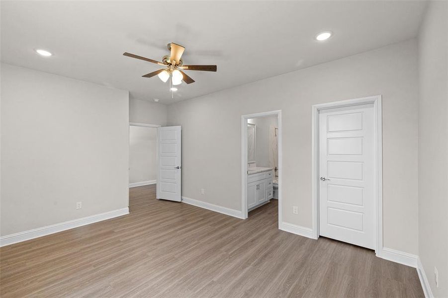 Unfurnished bedroom featuring ceiling fan, light hardwood / wood-style flooring, connected bathroom, and a closet