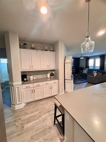 Kitchen featuring ceiling fan, white cabinets, light hardwood / wood-style flooring, and decorative light fixtures