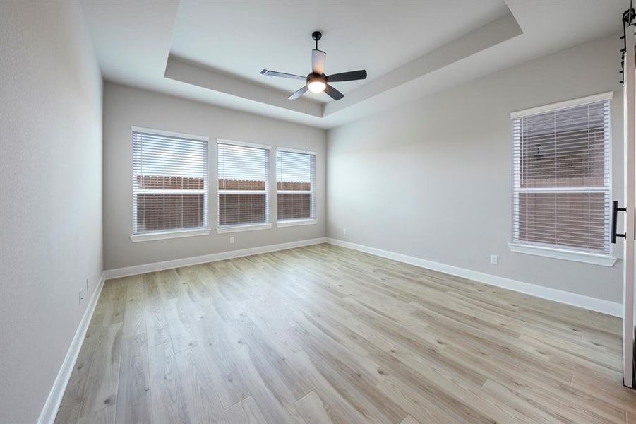 Located in the back corner of the home, the master bedroom features high ceilings with a ceiling fan and vinyl plank floors.