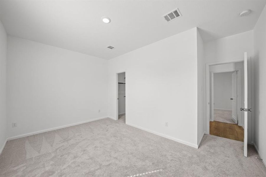 Bedroom 2 with neutral walls and carpeted flooring, featuring recessed lighting and walk-in closet.