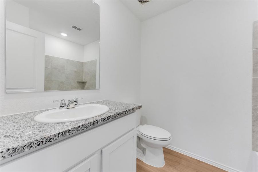 Bathroom with vanity, toilet, walk in shower, and hardwood / wood-style floors