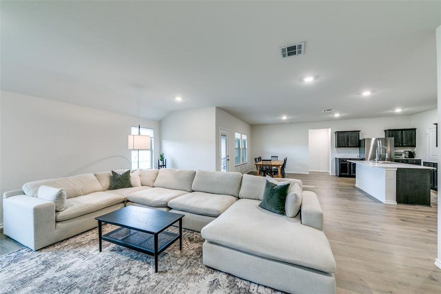 Living room with light wood-type flooring and vaulted ceiling