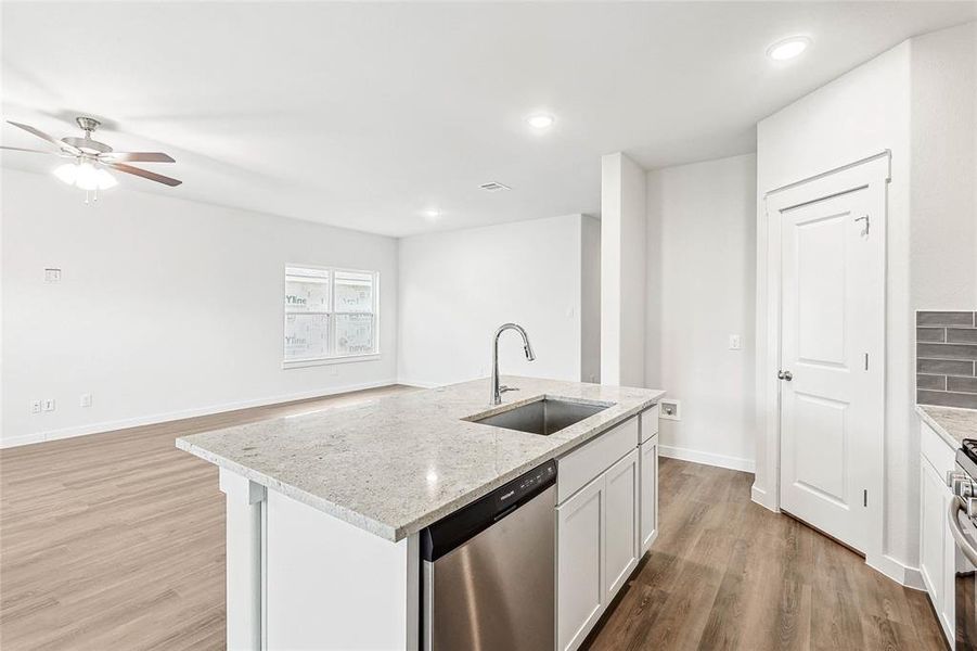 Kitchen with stainless steel appliances, sink, a kitchen island with sink, light wood-type flooring, and ceiling fan