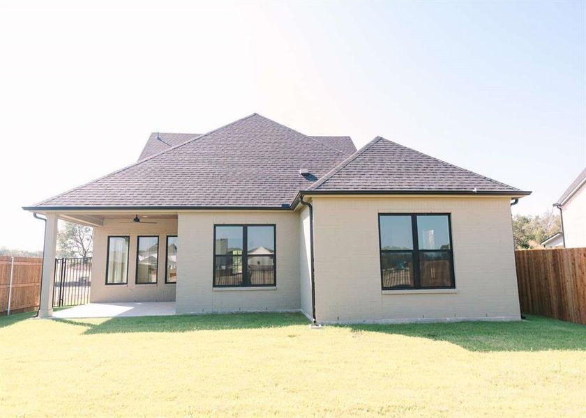 Rear view of property featuring a lawn and a patio