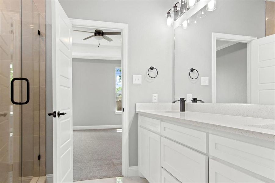 Bathroom with vanity, a shower with shower door, and ceiling fan