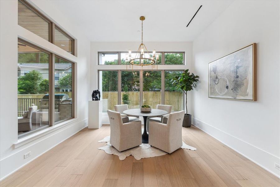 BREAKFAST ROOM:  Bathed in natural light pouring through expansive windows, this inviting space offers a seamless blend of comfort and style, inviting you to start your day in tranquility and elegance.